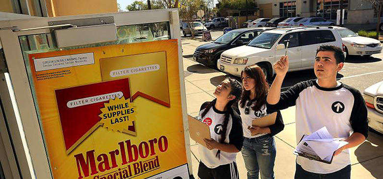 Group of evaluators looking at tobacco advertisement outside of gas station