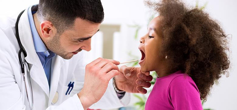 Doctor uses tongue depressor to look at child's throat